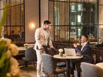 Two men in suits having a business meeting in a modern café setting. Two men in suits having a business meeting in a modern café setting.
