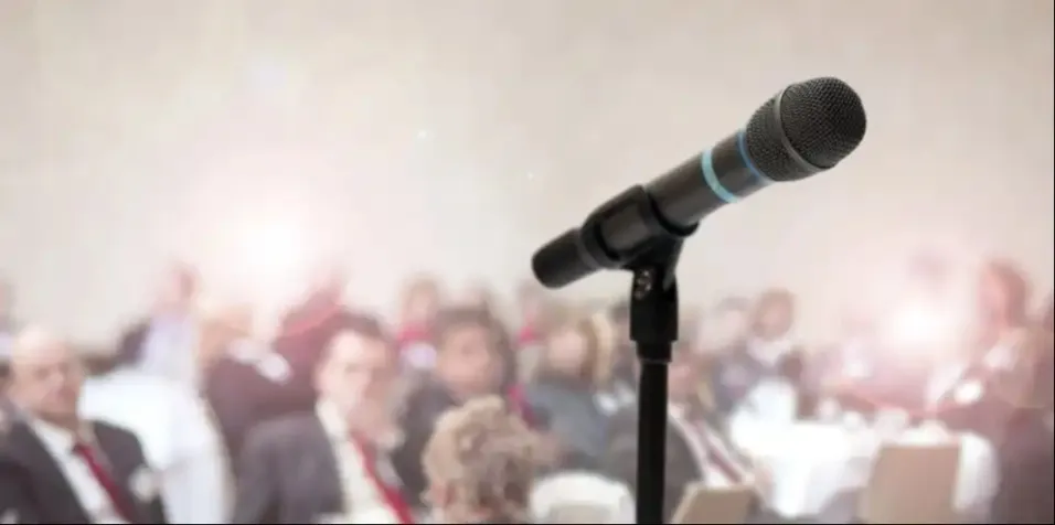 MIc on a stage in front of a crowd.
